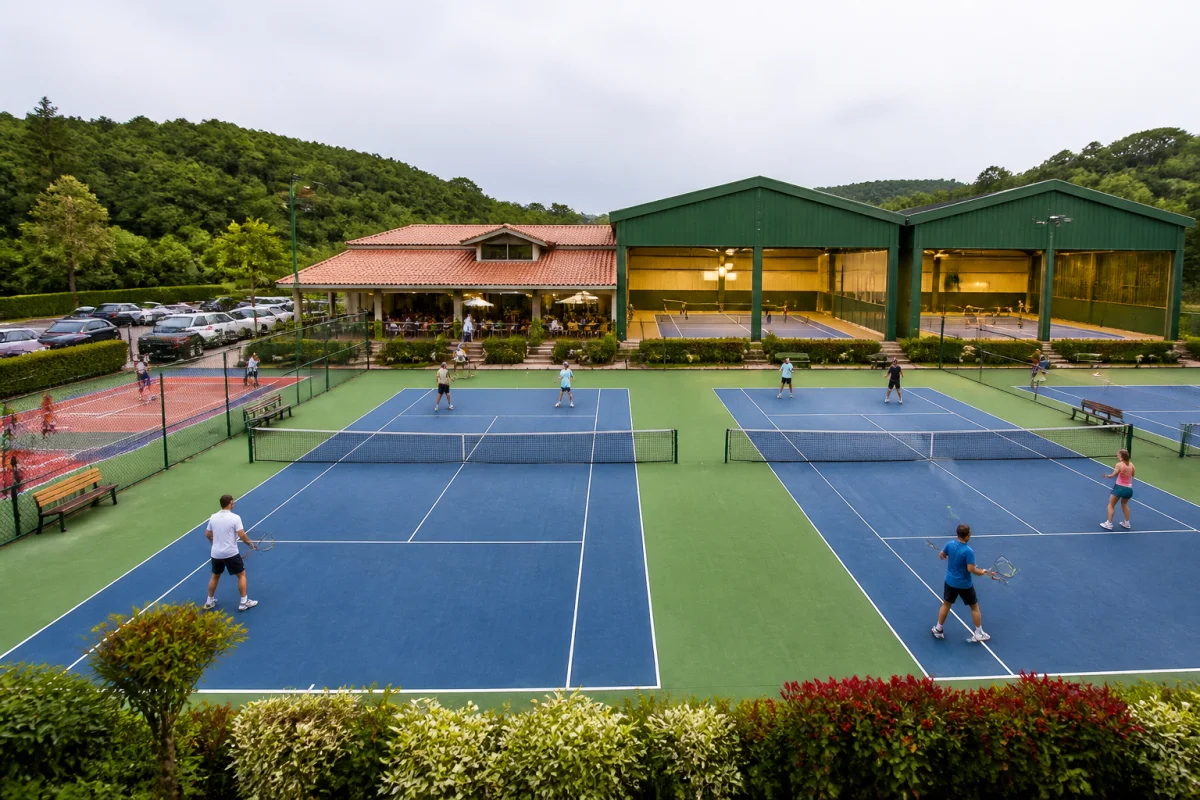 Club de tennis Charly accueillant, avec adultes et enfants jouant sur plusieurs courts extérieurs et couverts.
